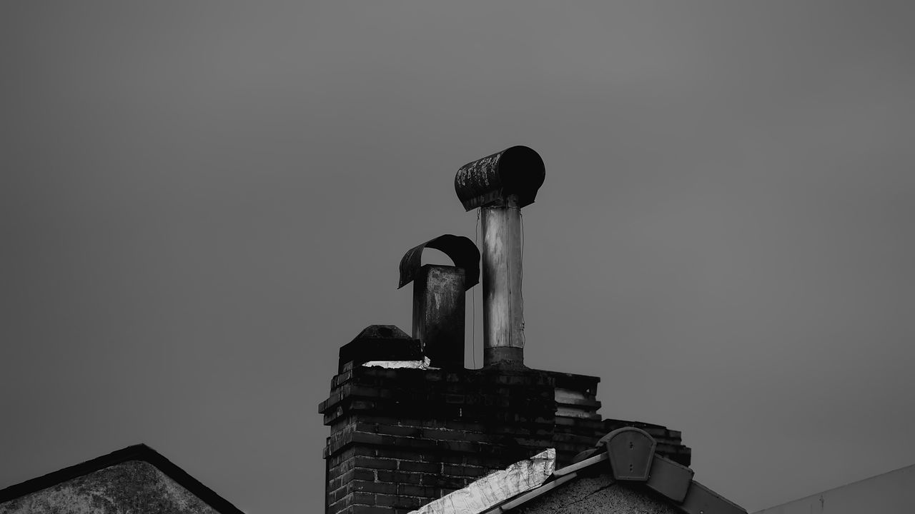 Monochrome image of a rustic chimney and rooftop, evoking a nostalgic feel.